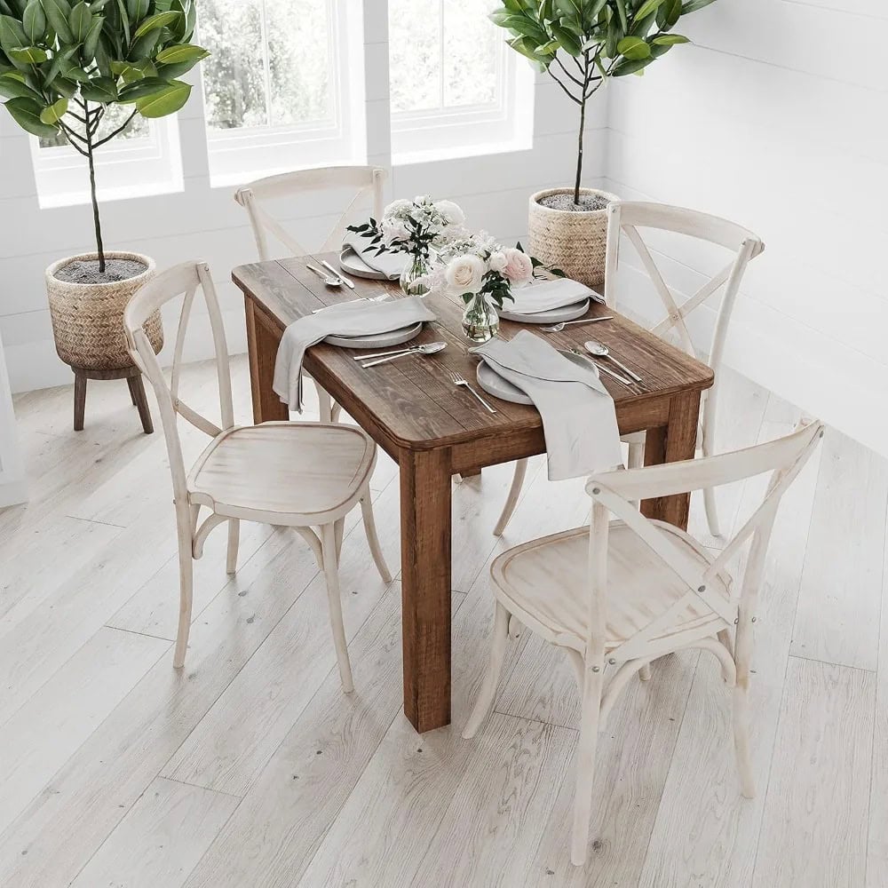 Stylish wooden dining table with white chairs, adorned with fresh flowers, in a bright, modern room featuring potted greenery for a cozy dining ambiance.