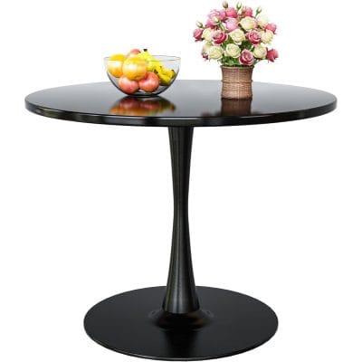 A sleek black round table featuring a glass bowl of colorful fruits and a basket of pink and white roses, perfect for home decor or a cozy cafe setting.