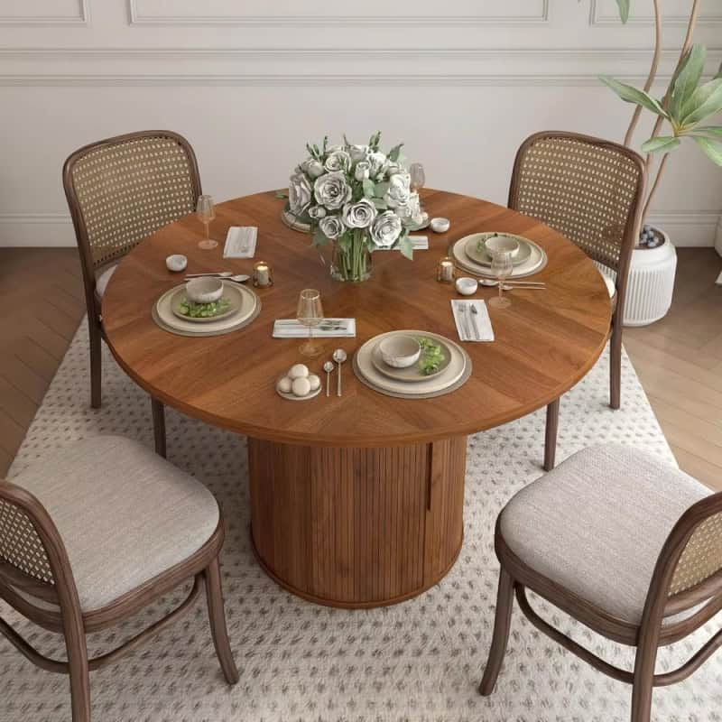 Stylish round dining table with beautiful chairs, floral centerpiece, and fine tableware, ideal for elegant home or restaurant dining settings.