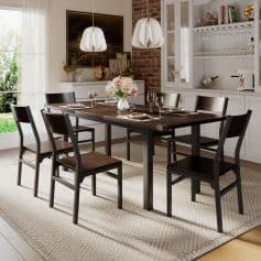 Elegant dining room with black wood table, six matching chairs, white china, wine glasses, floral centerpiece, and contemporary decor.