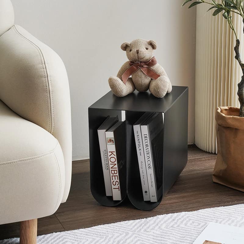 A stylish black optical display stand holding ophthalmology books, topped with a cute teddy bear, situated next to a white sofa in a cozy, modern living space.