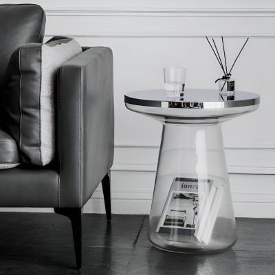 Stylish modern black leather sofa with a sleek silver side table holding a glass of water and decorative diffuser.