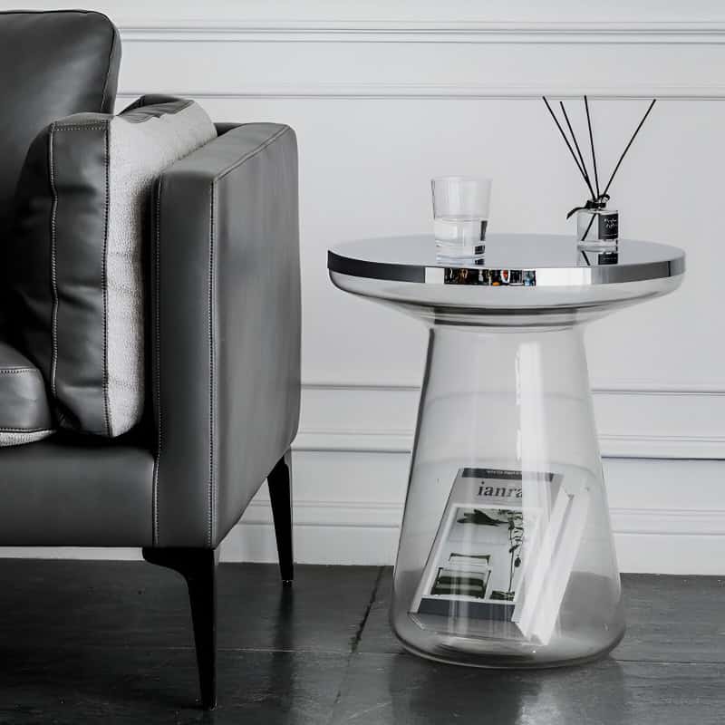 Stylish modern black leather sofa with a sleek silver side table holding a glass of water and decorative diffuser.