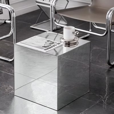 A sleek, reflective mirror cube side table in a contemporary office setting, enhanced with a stylish coffee mug, perfect for modern interior decor and versatile furniture solutions.