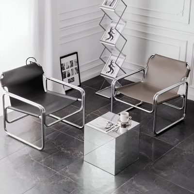 Contemporary seating in a minimalist optical store with chrome-framed chairs, a mirrored side table, artwork, and magazine rack for a fashionable eyewear shopping experience.