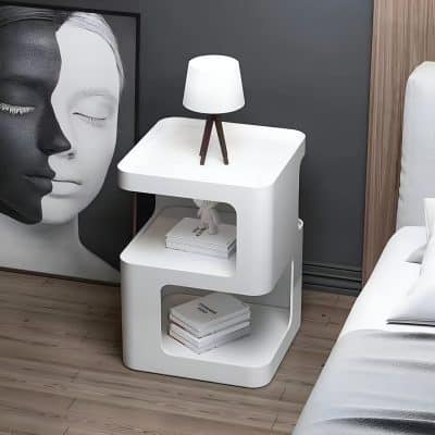 A sleek white bedroom nightstand featuring two open shelves filled with books and topped with a contemporary table lamp. Perfect for stylish bedroom organization and decor.