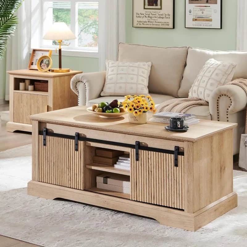 Bright living room featuring a natural wood coffee table with sliding barn doors, complemented by a white sofa, soft pillows, and stylish side table, creating a cozy and elegant ambiance.