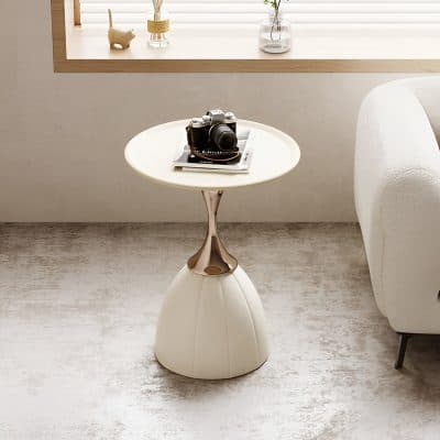 A sleek camera placed on a stylish white side table with a minimalistic design, located in a bright, contemporary interior space near a window with decorative items on the sill.