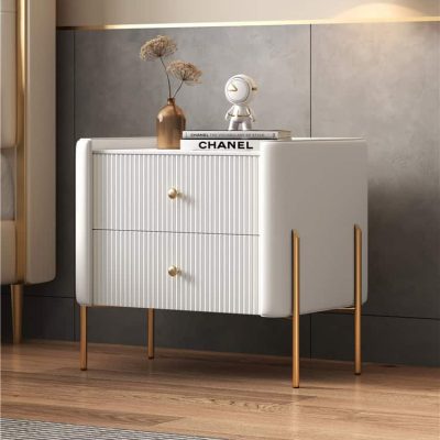 Elegant white sideboard with gold legs and knobs, featuring stylish decor including a vase with dried flowers and fashion books. Perfect for contemporary home or clinic decor.