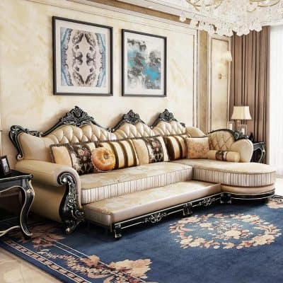 Luxurious antique-style cream and black upholstered sofa with ornate carved wood details, complemented by decorative pillows, modern artwork, and a chandelier in a sophisticated interior setting.