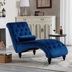 Elegant blue velvet chaise lounge with tufted design, nailhead trim, and rolled bolster cushion perfect for stylish living rooms and modern decor.