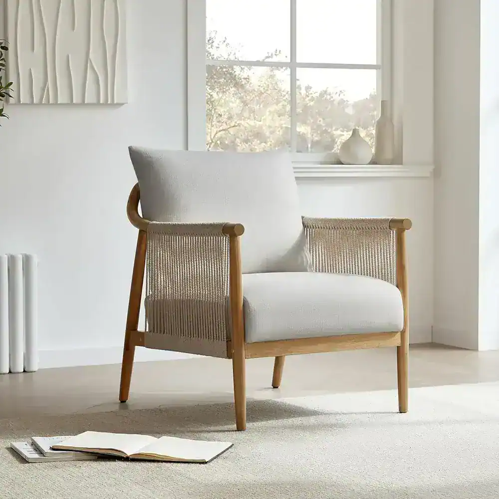 A modern white armchair with a wooden frame and woven rattan sides, perfect for stylish home or office decor. Bright natural light enhances the cozy and contemporary atmosphere.