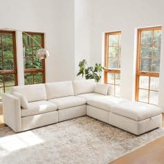 Bright living room with white sectional sofa, natural light, and wooden window frames, creating a cozy and inviting space for relaxation and social gatherings.