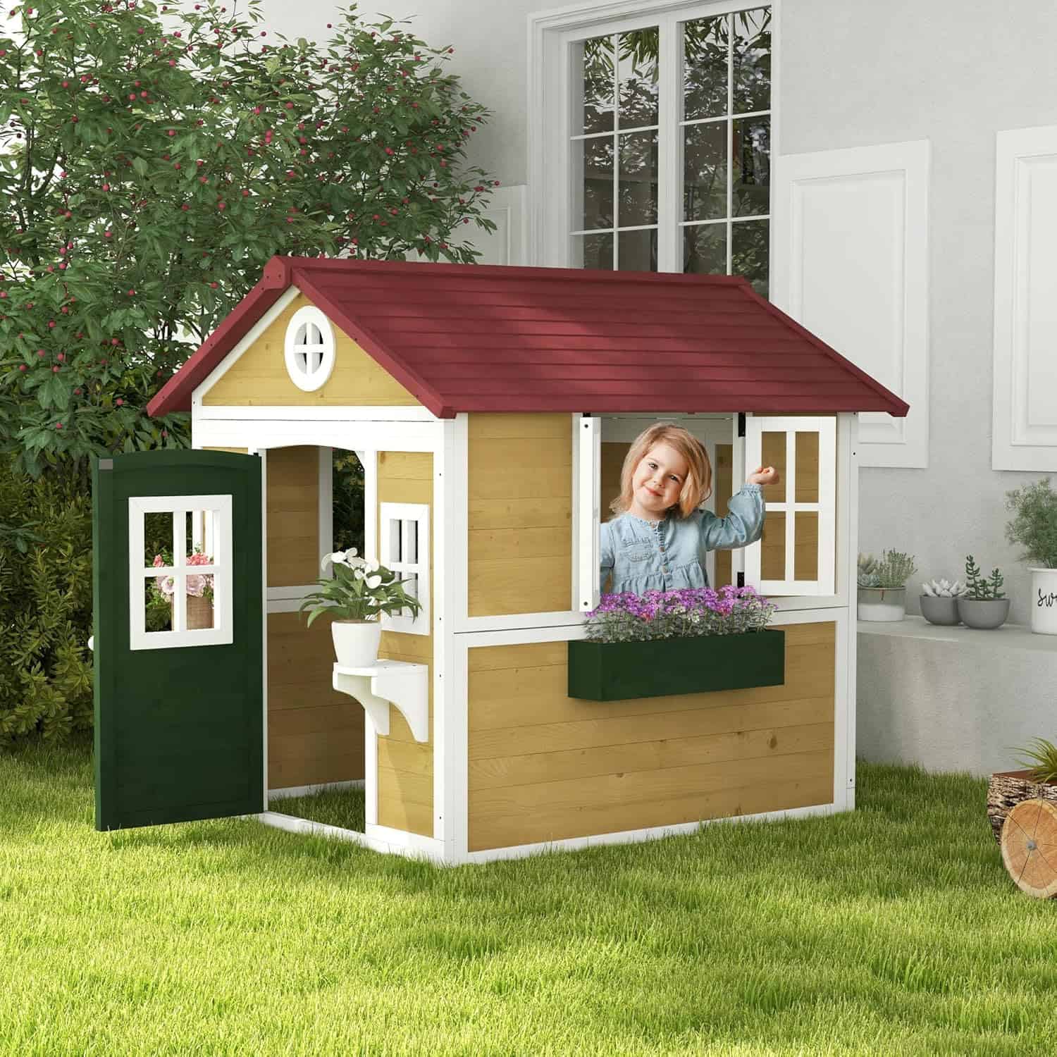 Bright yellow and white children's playhouse with a red roof, featuring a smiling young girl peeking out the window, surrounded by greenery and potted plants in a backyard setting.