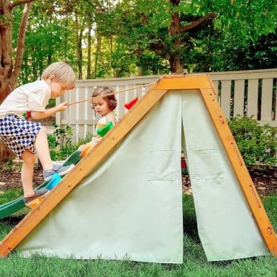 Kids playing with a teepee tent in a backyard garden, sunny outdoor scene with children, fun play area, safe outdoor toys, children’s entertainment, garden playset, outdoor kids activities, family-friendly outdoor space, backyard play equipment, child-friendly outdoor environment.