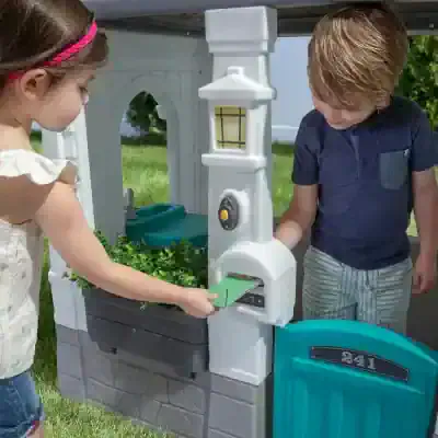 White plastic toy house for kids with mailbox and doorbell, outdoor playset for children.