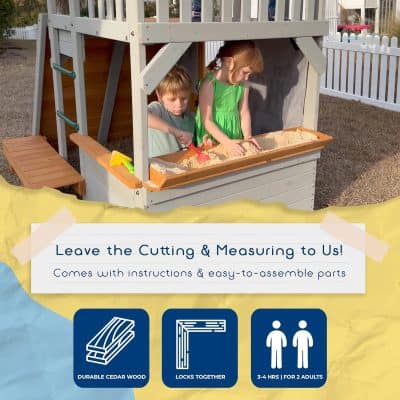 Children playing in sandbox under wooden playhouse, outdoor play area for kids, backyard sandbox with toy shovels, fun summer activity for children, family outdoor play space.