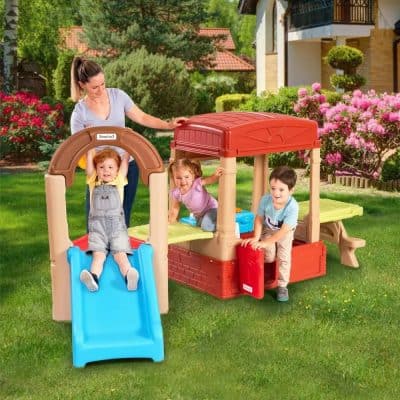 Colorful children's outdoor playhouse with slide, sandbox, and climbing features in a lush green backyard, ideal for outdoor fun and imaginative play for kids.