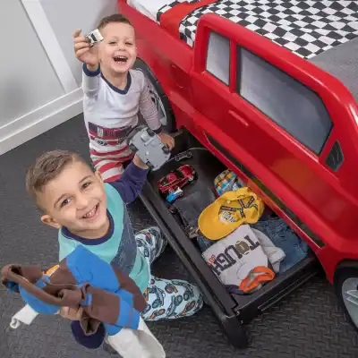 Kids playing with toy cars in a bedroom dressed as little drivers, enjoying imaginative play and developing motor skills. Perfect for children's toys, role play, and early childhood development.