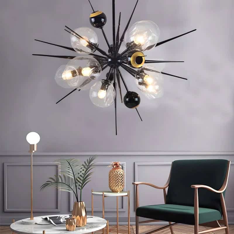 Modern black and gold chandelier with multiple glass bulbs, stylish interior living room decor with green armchair, marble coffee table, and decorative plants, perfect for contemporary home lighting.