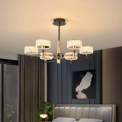 Elegant modern chandelier with multiple lampshades hanging above a stylish bedroom with dark blue accent wall and contemporary art.