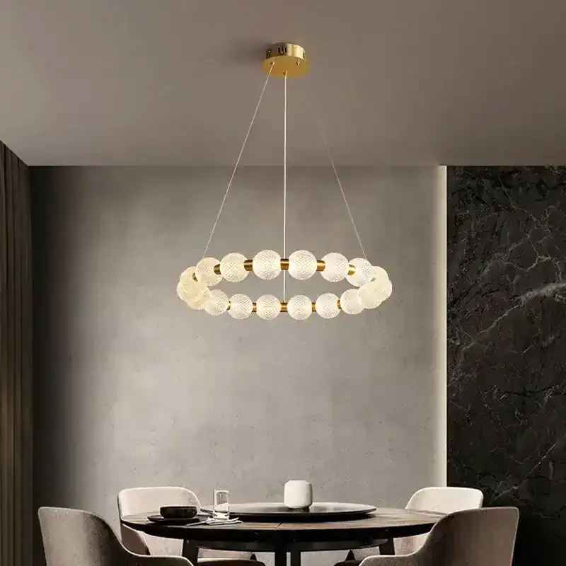 Elegant modern chandelier with spherical glass and gold accents hanging above a contemporary dining table. Perfect for sophisticated interior lighting in home or restaurant settings.