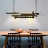Modern dining room with minimalist wooden table, black chairs, and contemporary geometric chandelier lighting, ideal for stylish home or restaurant interiors.