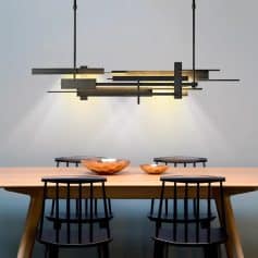 Modern dining room with minimalist wooden table, black chairs, and contemporary geometric chandelier lighting, ideal for stylish home or restaurant interiors.