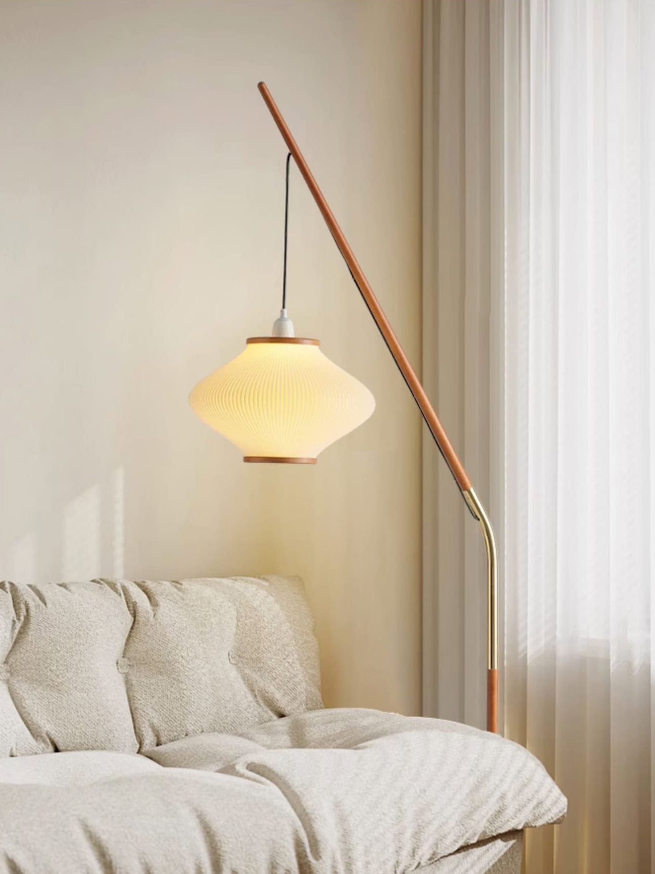 Elegant modern floor lamp with a warm glowing lampshade, standing beside a cozy beige sofa in a contemporary living room setting, ideal for stylish home decor and lighting solutions.