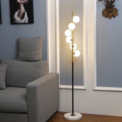 Modern floor lamp with white globes illuminated in stylish living room with gray sofa and artwork.