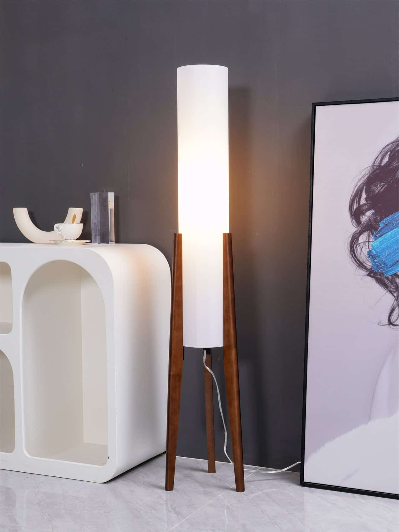 Modern floor lamp with wooden legs and white cylindrical shade, ideal for enhancing the ambiance of an optometry or optical store environment.