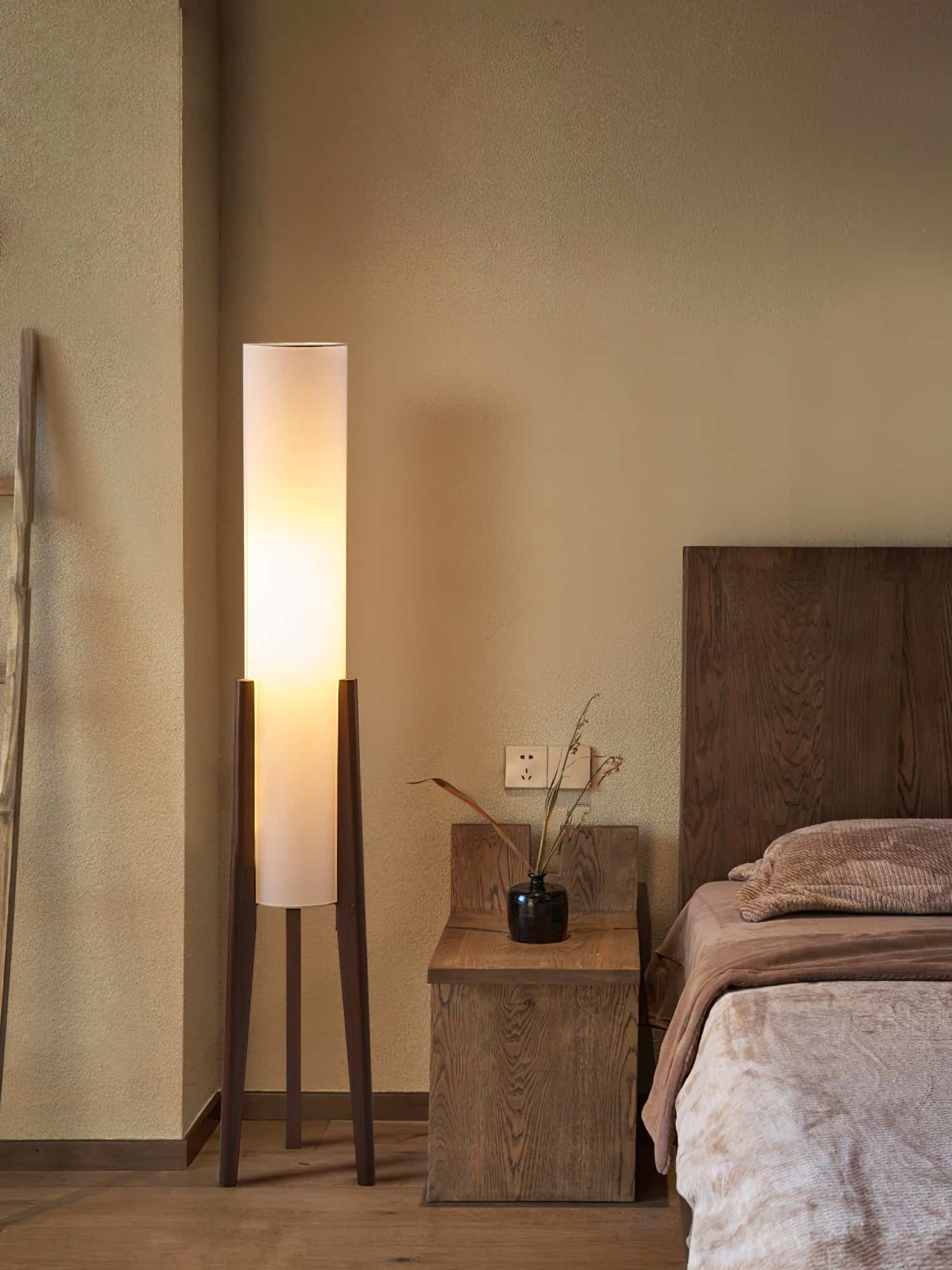 Elegant bedroom with a warm ambient light from a tall, modern floor lamp and cozy wooden furnishings, perfect for relaxation at Monalisa Store.