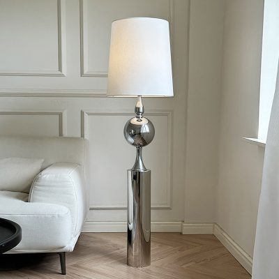 Modern chrome floor lamp with a white lampshade in a stylish living room setting.