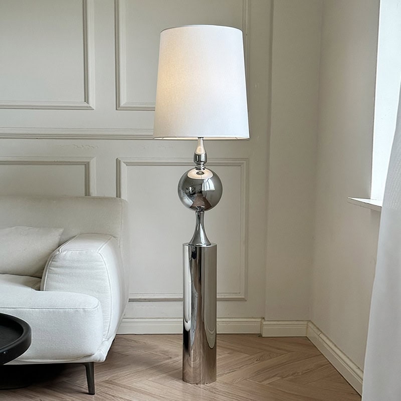 Modern chrome floor lamp with a white lampshade in a stylish living room setting.