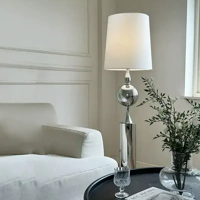 Elegant modern living room with a sleek chrome floor lamp, a white sofa, and stylish decor accents, perfect for a contemporary home offering comfort and minimalist aesthetic.