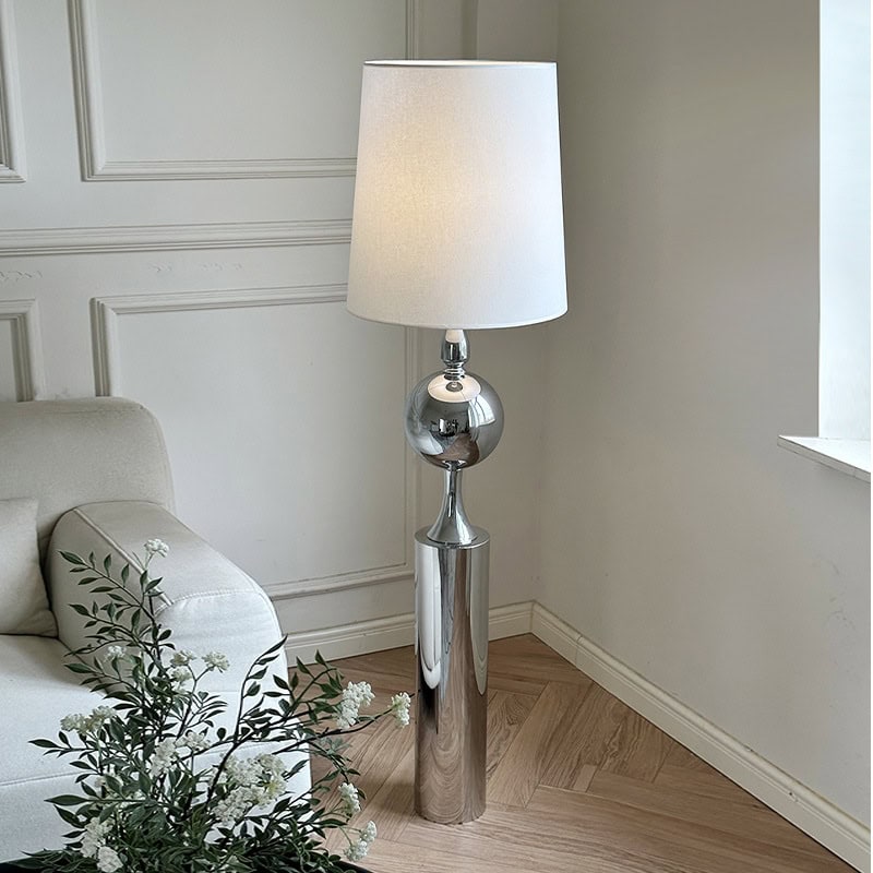 Luxury modern floor lamp with chrome finish and white lampshade in contemporary living room setting.