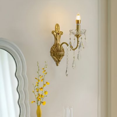 Elegant gold wall sconce with crystal accents illuminated in a luxury interior setting.