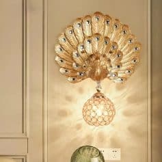 Peacock-inspired gold wall sconce with peacock feather design, ornate lighting fixture enhancing luxury interior decor.