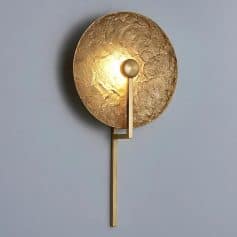 Gold textured wall sconce with modern lighting design for luxury interior decor.