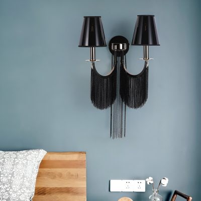 Black chandelier with chain accents and two black lampshades hanging on a modern bedroom wall.