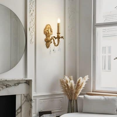 Elegant interior with ornate wall sconce, decorative mirror, marble fireplace, and cozy seating area featuring pampas grass decor, highlighting sophisticated home aesthetic and luxurious design.