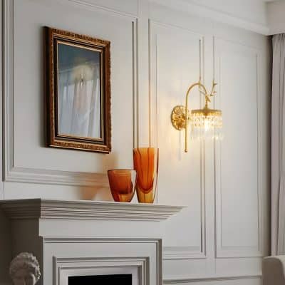 Elegant interior wall decor with classic white paneling, gold wall sconce, ornate framed mirror, and amber glass vases, showcasing a sophisticated and timeless aesthetic.