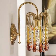 Elegant gold wall-mounted lamp with crystal and amber glass accents, ideal for luxury interior decor and enhancing ambiance in a sophisticated home or jewelry store setting.