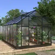 Modern black-framed glass greenhouse with lush plants inside, ideal for gardening and plant care, situated on a wooden deck with outdoor greenery and blue sky background.
