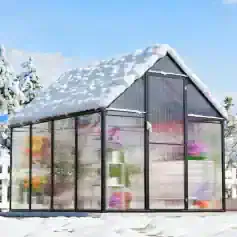 Garden greenhouse with snow on roof and colorful plants inside optimal for gardening in winter.