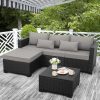 Outdoor patio furniture set with dark wicker design, cushions, and a small table with coffee mugs, flowers, and magazines, perfect for relaxing or entertaining in a garden or backyard setting.