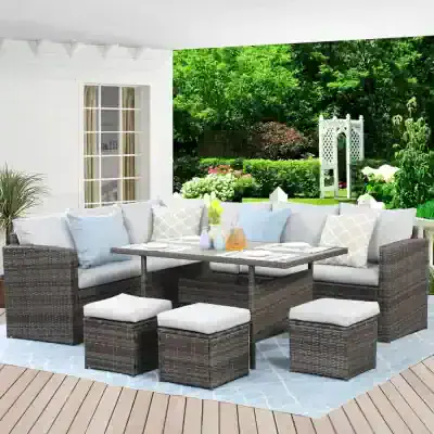 Stylish outdoor patio furniture set with wicker sectional sofa, ottomans, and a dining table, perfect for garden relaxation and entertaining in a lush backyard.