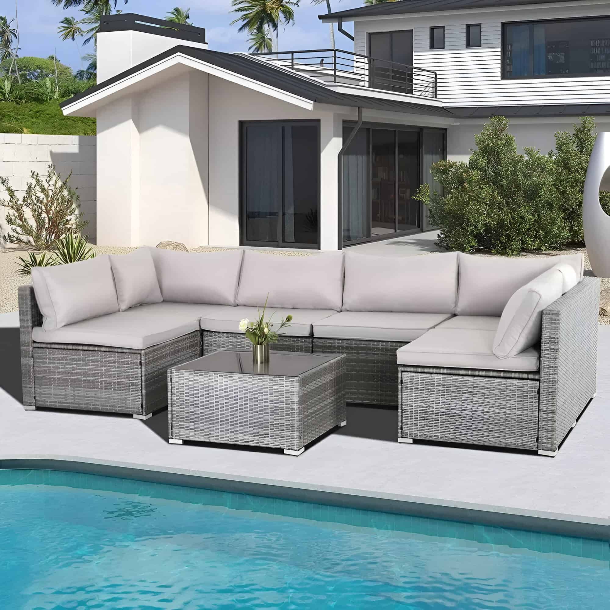 Modern outdoor lounge area with stylish sectional sofa, glass-topped coffee table, pool, and contemporary house, perfect for relaxing and entertaining in a luxurious residence.
