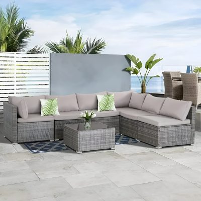 Modern outdoor patio furniture with plush cushions, wicker design, and tropical decor on a balcony overlooking the ocean. Perfect for relaxing and entertaining in style.