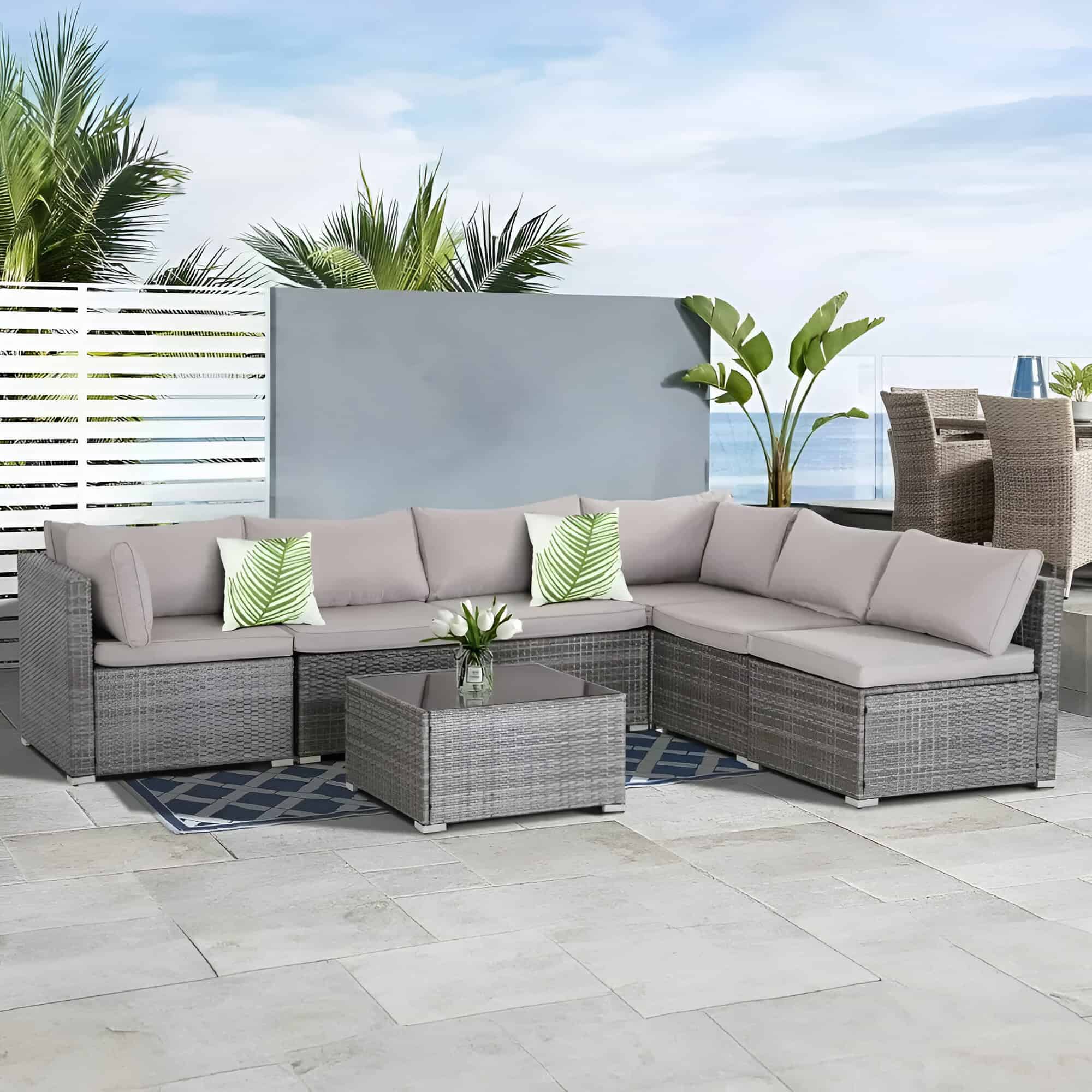 Modern outdoor patio furniture with plush cushions, wicker design, and tropical decor on a balcony overlooking the ocean. Perfect for relaxing and entertaining in style.